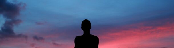 Person meditating at sunset